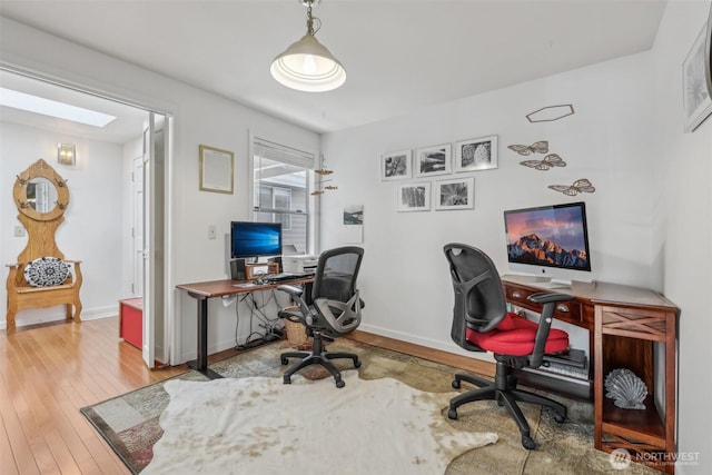 home office featuring hardwood / wood-style floors, baseboards, and a skylight