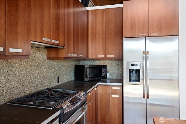 1408 12th Ave Unit 507, Seattle, WA 98122 - kitchen featuring stainless steel appliances, under cabinet range hood, brown cabinetry, dark countertops, and decorative backsplash