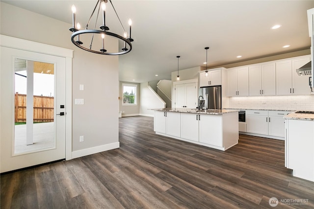 kitchen with decorative backsplash, an inviting chandelier, dark wood finished floors, stainless steel fridge, and white cabinetry