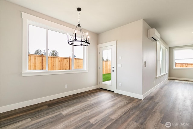 unfurnished dining area with baseboards, a notable chandelier, a wall mounted air conditioner, and dark wood-type flooring