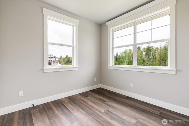 unfurnished room with baseboards and dark wood finished floors