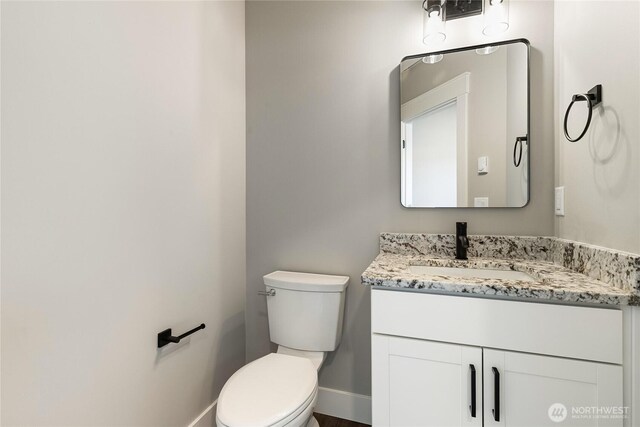 bathroom featuring baseboards, vanity, and toilet