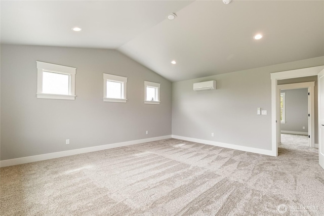 spare room with baseboards, vaulted ceiling, light carpet, and a wall mounted air conditioner
