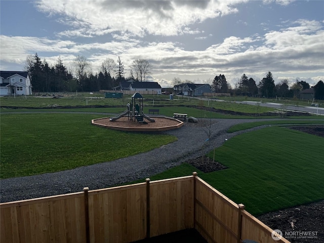 view of home's community featuring a yard, fence, and playground community