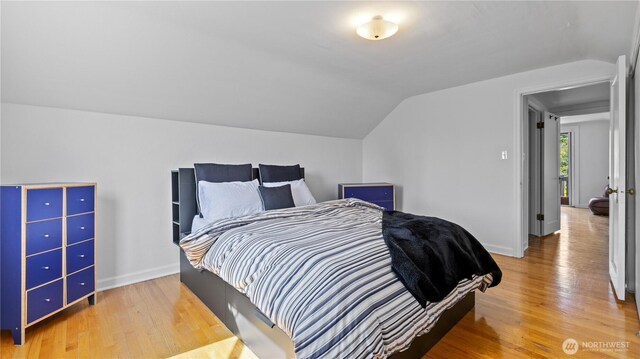 bedroom featuring lofted ceiling, baseboards, and wood finished floors