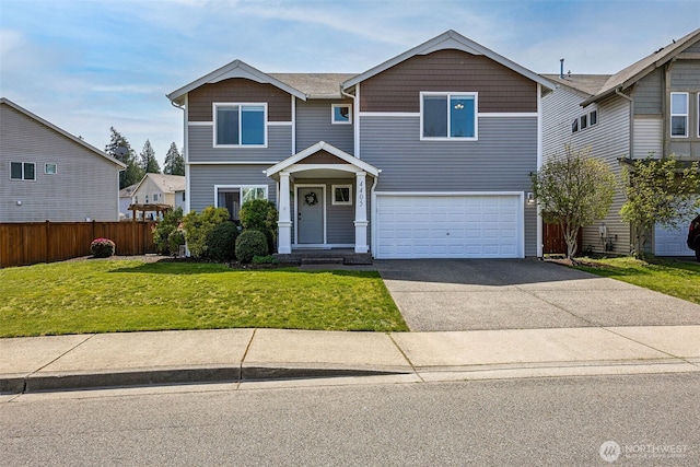 traditional-style house with fence, driveway, a front yard, and a garage