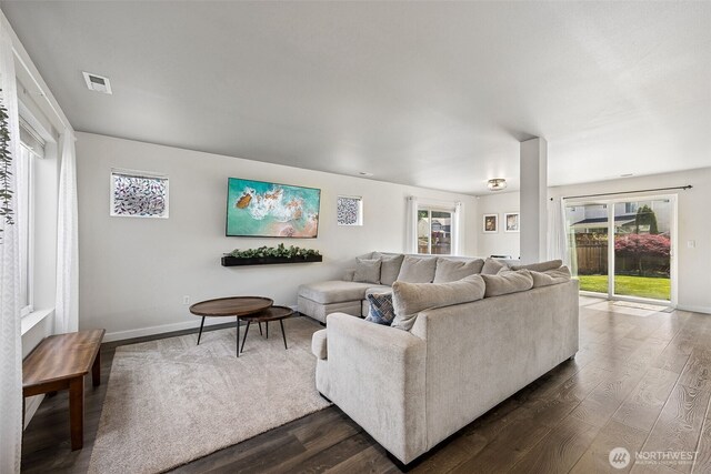 living area with baseboards, visible vents, and dark wood-type flooring
