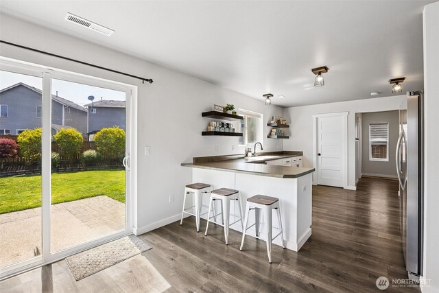 kitchen featuring visible vents, open shelves, a sink, freestanding refrigerator, and a wealth of natural light