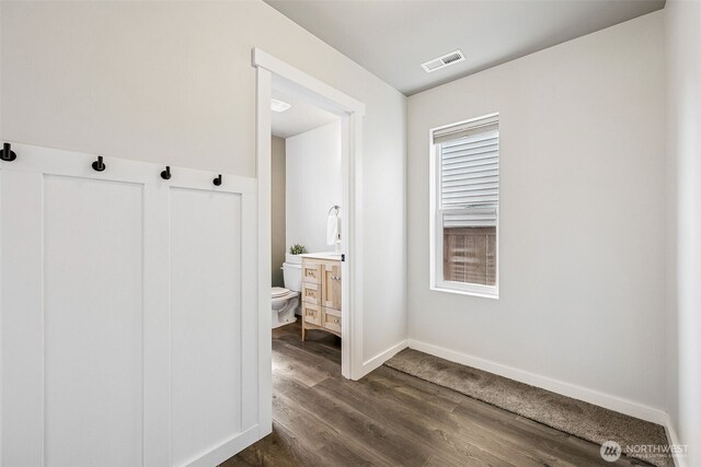 interior space featuring visible vents, wood finished floors, vanity, baseboards, and toilet
