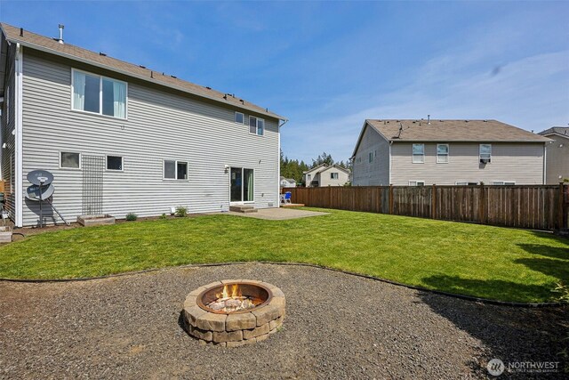 back of property featuring a yard, fence, a patio area, and an outdoor fire pit