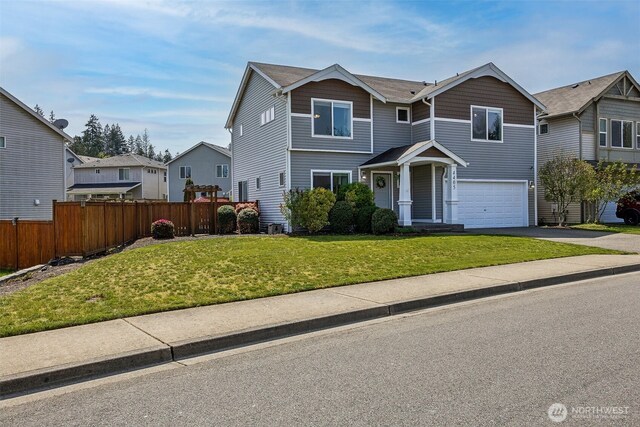 traditional-style home with driveway, a front yard, a residential view, a garage, and fence