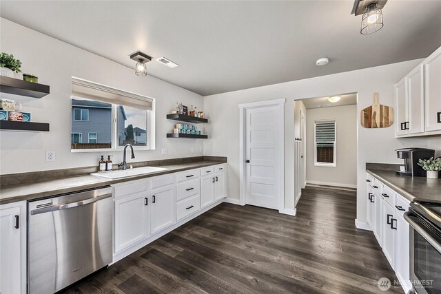 kitchen with a sink, open shelves, appliances with stainless steel finishes, and dark countertops