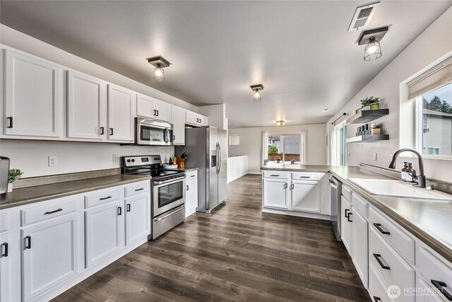 kitchen with visible vents, appliances with stainless steel finishes, a sink, a peninsula, and white cabinetry