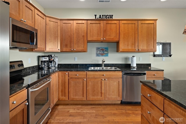 23154 Sunserra Loop NW Unit B15, Quincy, WA 98848 - kitchen with brown cabinets, appliances with stainless steel finishes, a sink, and light wood-type flooring