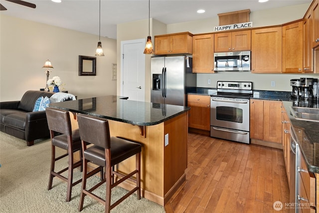 23154 Sunserra Loop NW Unit B15, Quincy, WA 98848 - kitchen featuring light wood finished floors, a kitchen breakfast bar, a sink, brown cabinets, and appliances with stainless steel finishes