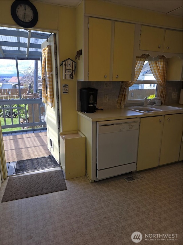 kitchen featuring a sink, decorative backsplash, white dishwasher, visible vents, and light countertops