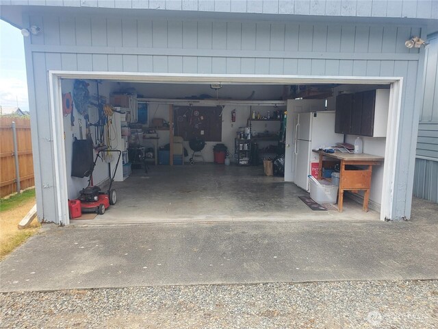 garage featuring fence and freestanding refrigerator