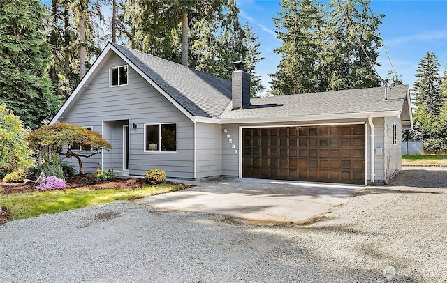view of front of property with a chimney, an attached garage, driveway, and a shingled roof