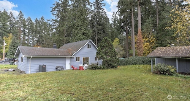 rear view of house featuring a lawn, central AC, and a shingled roof