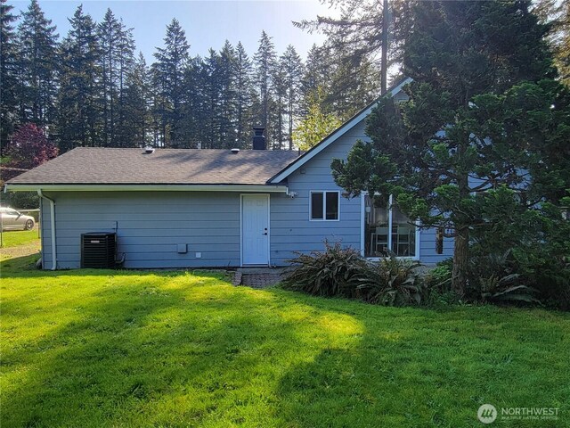 back of property featuring a lawn, roof with shingles, and cooling unit