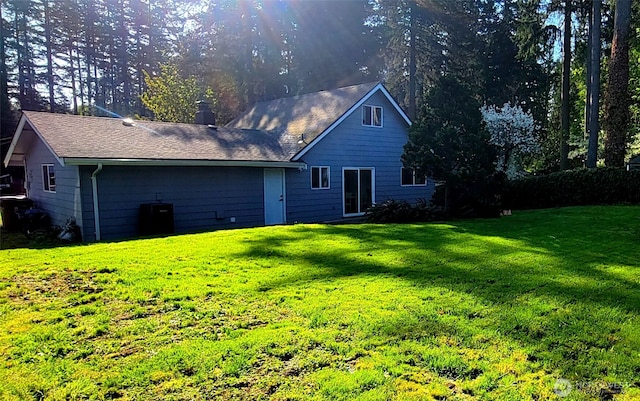 rear view of property with central air condition unit and a yard