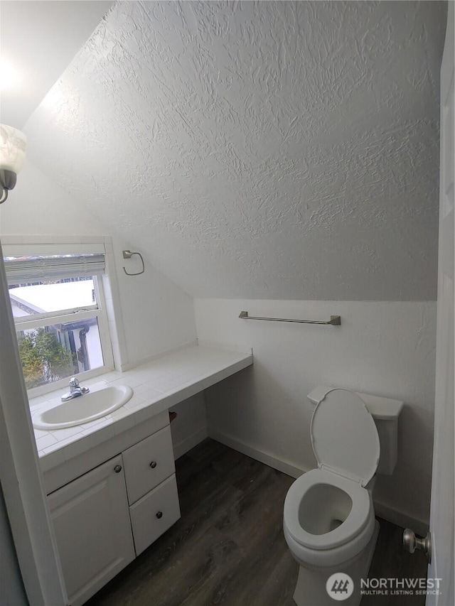 1700 California Ave S, Long Beach, WA 98631 - bathroom featuring toilet, a textured ceiling, vanity, wood finished floors, and lofted ceiling