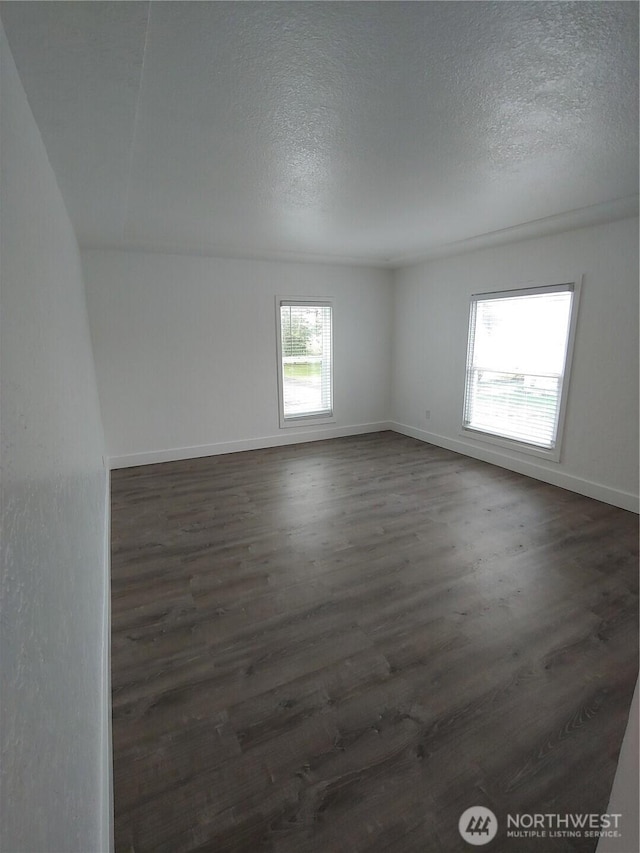 1700 California Ave S, Long Beach, WA 98631 - empty room featuring baseboards, a textured ceiling, and dark wood-style floors