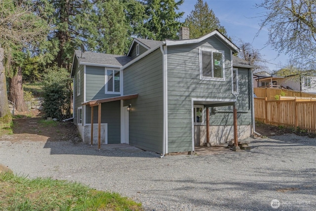 exterior space featuring roof with shingles, fence, and a chimney