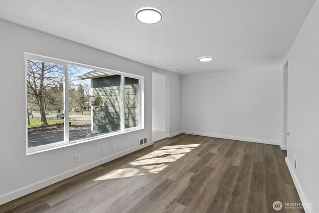 unfurnished room with visible vents, baseboards, and wood finished floors