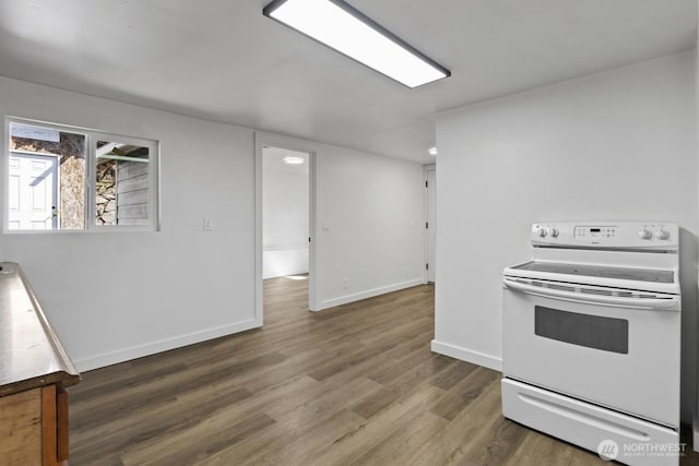 kitchen with white electric range, baseboards, and wood finished floors