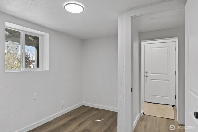 interior space featuring baseboards, a textured ceiling, and wood finished floors