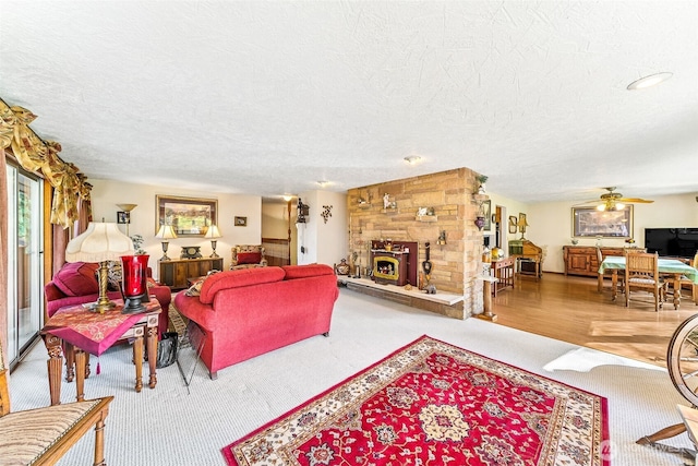 carpeted living room with a ceiling fan, a fireplace, and a textured ceiling