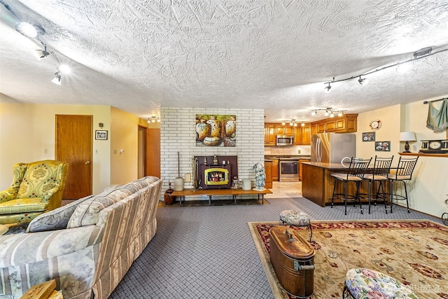 carpeted living room featuring a brick fireplace, a textured ceiling, and track lighting