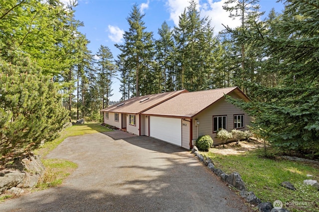 view of front facade featuring driveway, a garage, a shingled roof, and a front lawn