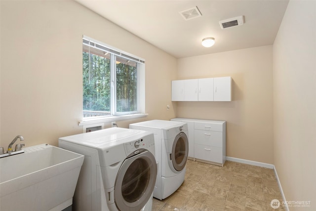 laundry area featuring washer and clothes dryer, cabinet space, and baseboards