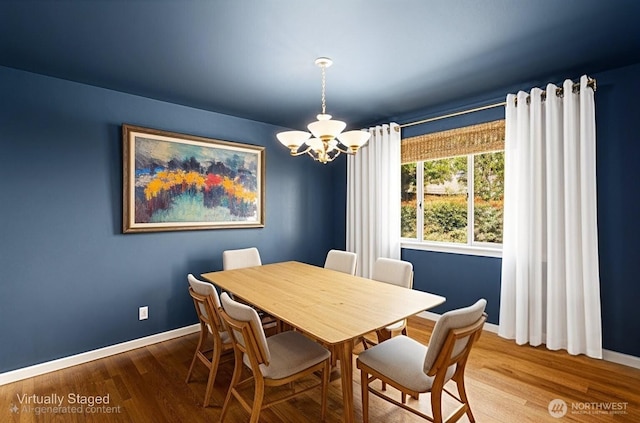 dining room featuring a chandelier, baseboards, and wood finished floors
