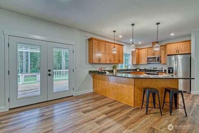 2822 200th Ave SW, Lakebay, WA 98349 - kitchen featuring appliances with stainless steel finishes, a peninsula, dark countertops, brown cabinetry, and light wood finished floors