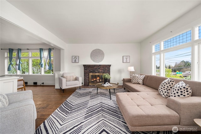 living room with wood finished floors, baseboards, and a brick fireplace