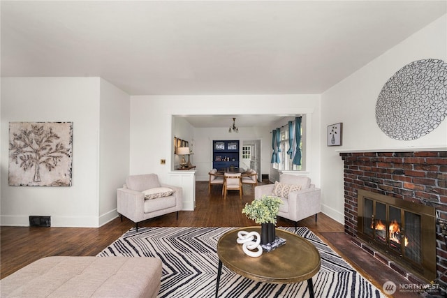living area featuring wood finished floors, baseboards, and a brick fireplace