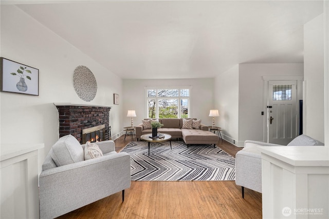 living room with a fireplace, baseboards, and wood finished floors