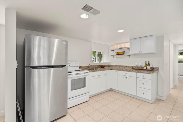 kitchen featuring visible vents, white cabinets, freestanding refrigerator, and electric stove