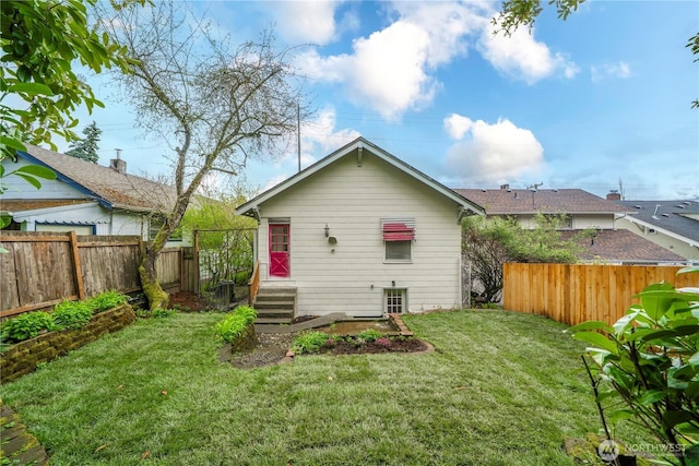 back of property featuring entry steps, a fenced backyard, and a lawn