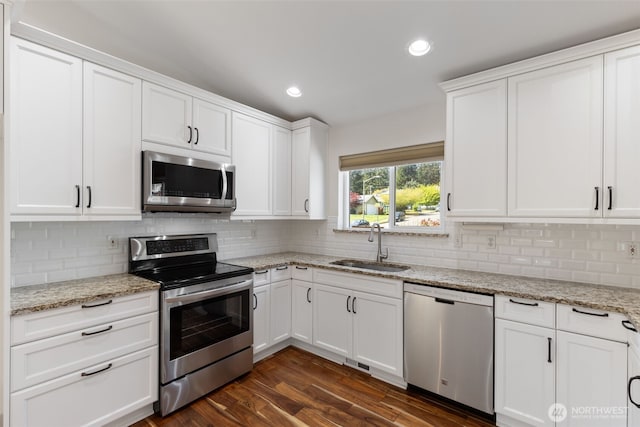 kitchen with white cabinetry, stainless steel appliances, decorative backsplash, and a sink