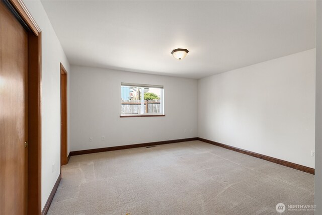 unfurnished bedroom with light colored carpet, a closet, and baseboards
