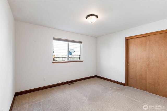 unfurnished bedroom with baseboards, visible vents, a closet, and carpet flooring