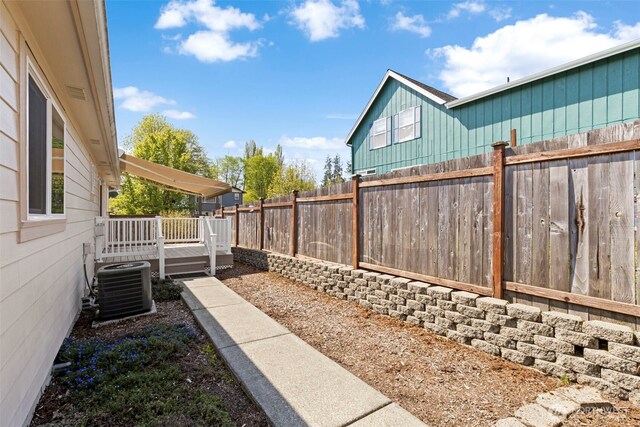 view of yard featuring a deck, central AC, and a fenced backyard