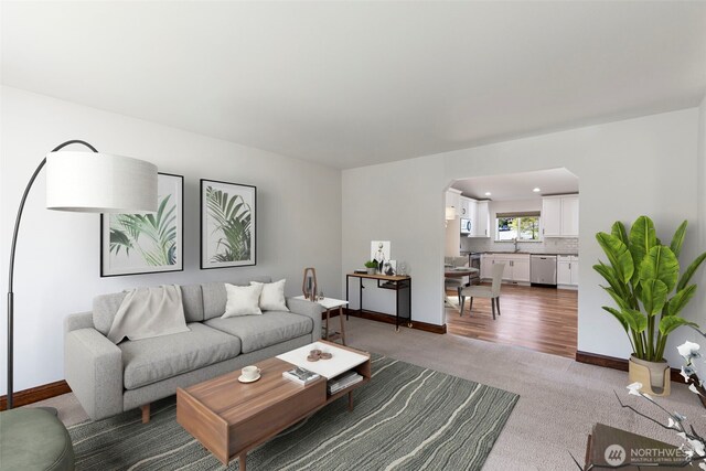 living area featuring baseboards, carpet flooring, and arched walkways