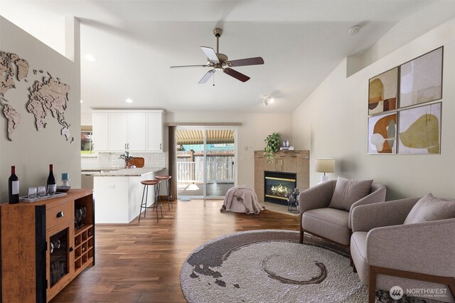 living room with ceiling fan, dark wood-style flooring, recessed lighting, vaulted ceiling, and a tiled fireplace