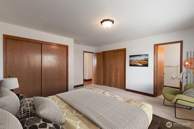 bedroom featuring baseboards, light colored carpet, and multiple closets