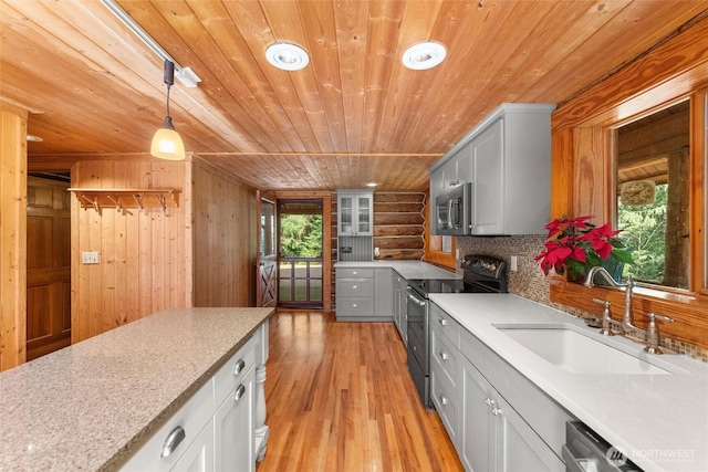 kitchen with wooden ceiling, a sink, light countertops, appliances with stainless steel finishes, and light wood finished floors